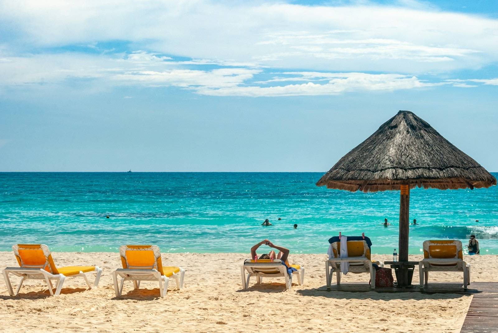 Palapa y camastros frente al mar turquesa de Cancún