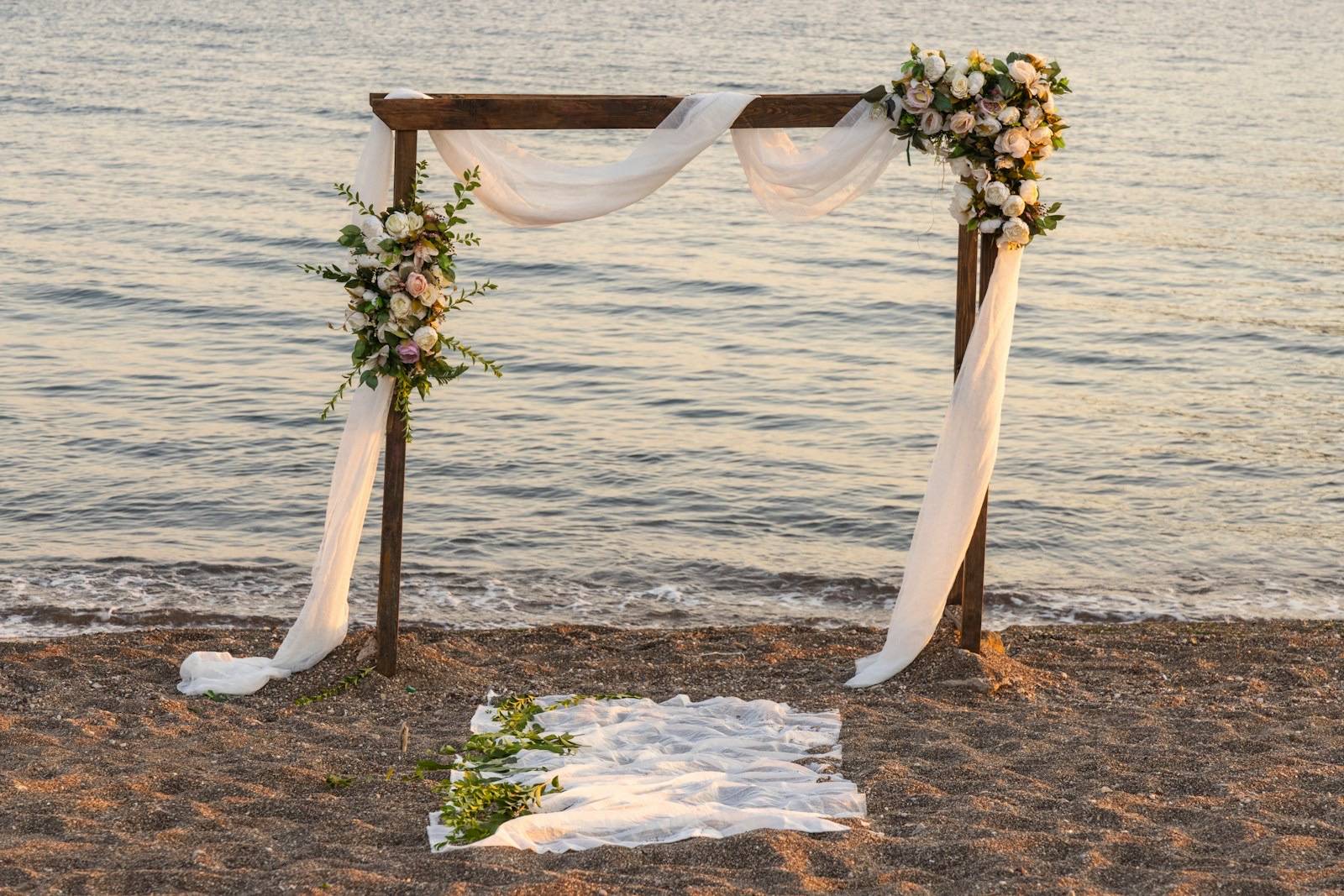 Arco de boda con flores y telas frente al mar